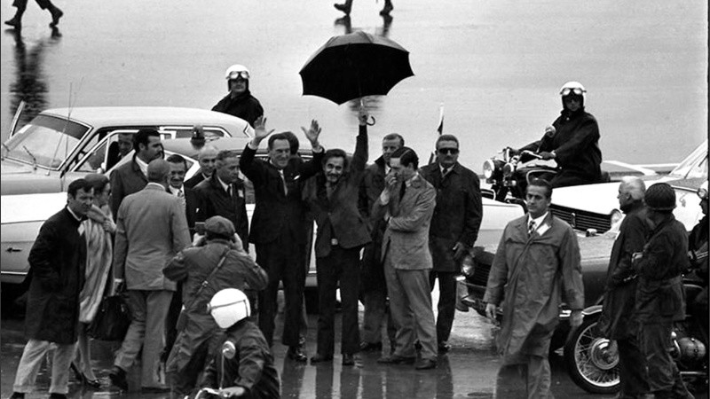 Perón tras bajar del avión, junto a José Ignacio Rucci y su paraguas.