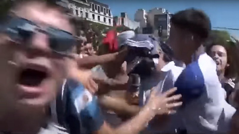 El periodista alemán entre hinchas tratando de hacer el móvil para la TV de su país.