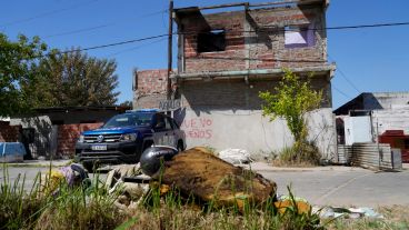 El patrullero custodia una de las casas saqueadas y al lado asoman las cosas devueltas.