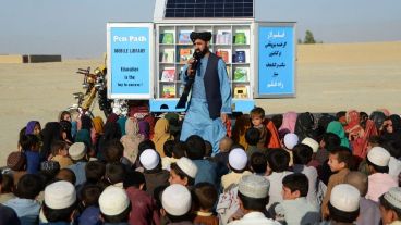 Matiullah Wesa, habla a un grupo de infantes durante una clase, junto a su biblioteca móvil, en el distrito de Spin Boldak, en la provincia de Kandahar, el 17 de mayo de 2022.