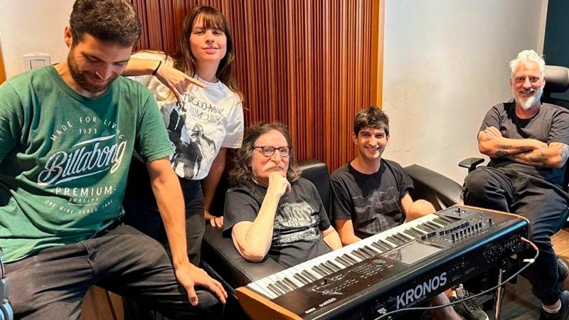 Charly García en el estudio, sentado en su teclado y acompañado por sus músicos.