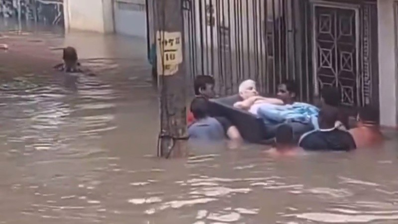 Un hombre mayor es trasladado en un colchón flotante en medio de la inundación.