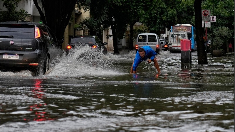 Los vecinos intentan destapar las bocas de tormenta.