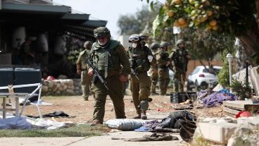 Soldados israelíes caminan junto a un cadáver en el kibutz de Kfar Aza, junto a la frontera con Gaza.