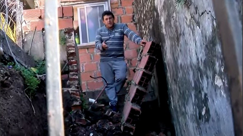 Daniel sobre el escombro que provocó el derrumbe de la pared de contención de la barranca.