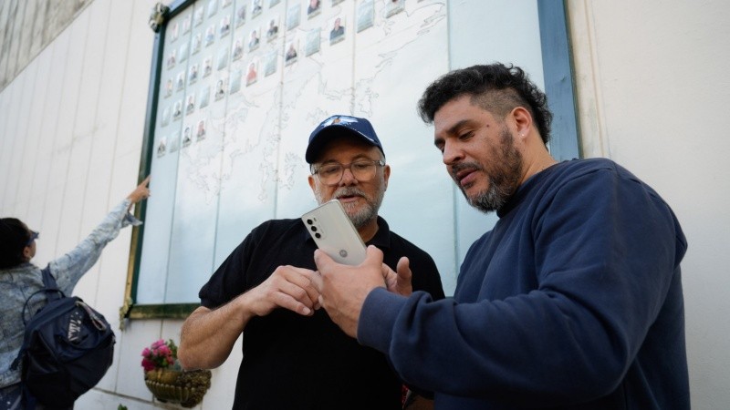 Fernando Vitale y Santiago Gallo, entre le mural con las cenizas de Felipe y los otros 80 homenajes.