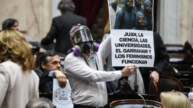 El diputado usó una máscara, vistió guardapolvo blanco y levantó un cartel con reclamos sociales