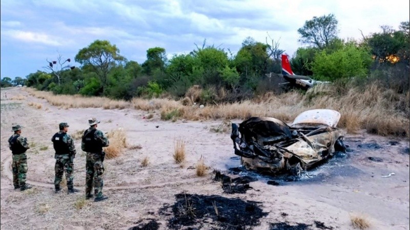Gendarmes custodiando la avioneta siniestrada y el vehículo incendiado.