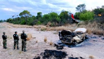 Gendarmes custodiando la avioneta siniestrada y el vehículo incendiado.