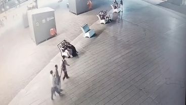 Los tres chicos llevan el cartel robado a cuestas.