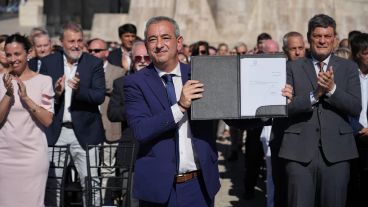 El intendente muestra orgulloso la ordenanza promulgada al pie del Monumento a la Bandera.