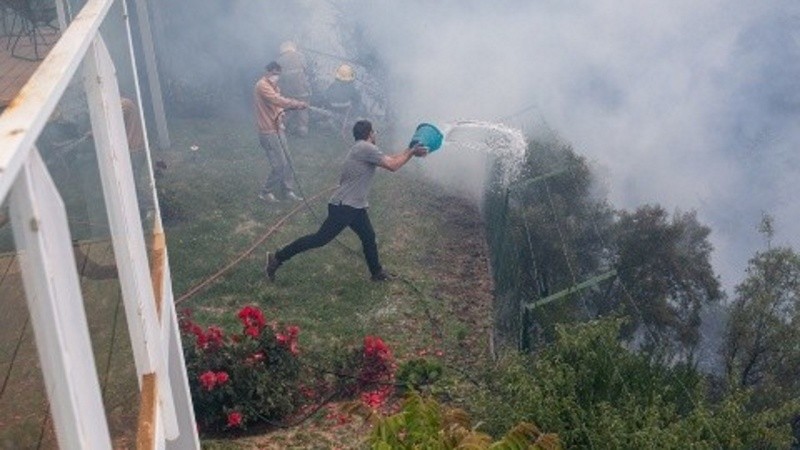 Bomberos y vecinos intentando contener las llamas.