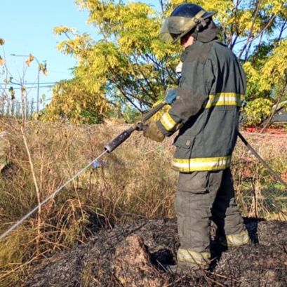 Un bombero apagando pastos quemados.