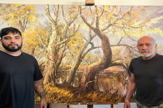 Los artistas Mario Domínguez Teixeira y su hijo Rodrigo Domínguez, posando con una obra del pintor del río y antedecesor de ambos.