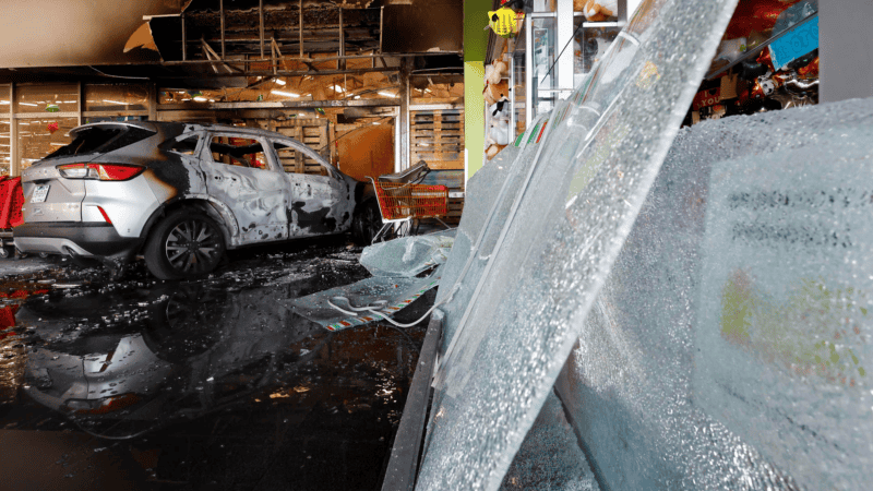 Fotografía de un vehículo incendiado en un centro comercial por presuntos integrantes del crimen organizado este domingo. (EFE)