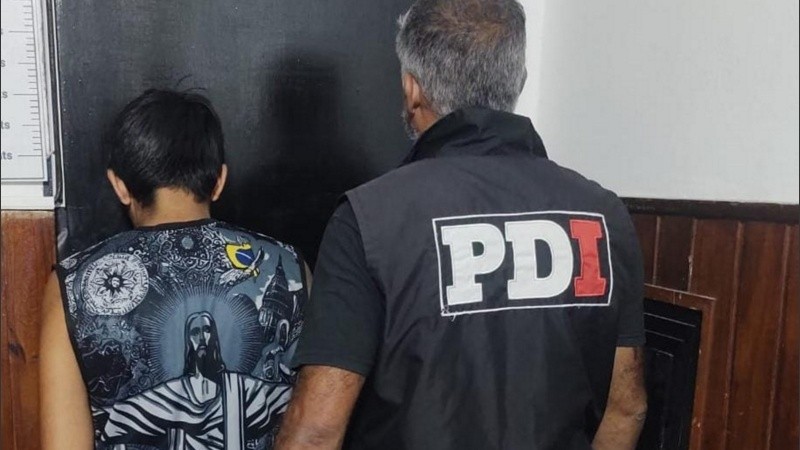 El sospechoso, de espaldas, es exhibido por el personal de la PDI.
