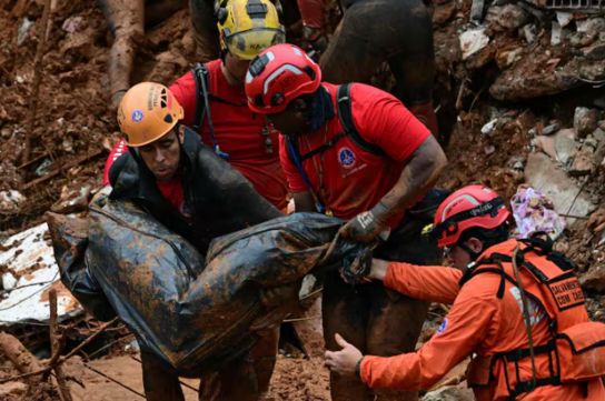 Los bomberos cargan un cadáver encontrado entre los escombros tras un deslizamiento de tierra causado por las fuertes lluvias en el Barrio Parque Jardim Burnier, en Juiz de Fora, Estado de Minas Gerais, Brasil.