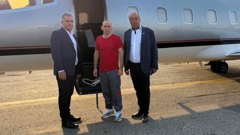 Gallo junto a funcionarios antes de abordar el vuelo de regreso.