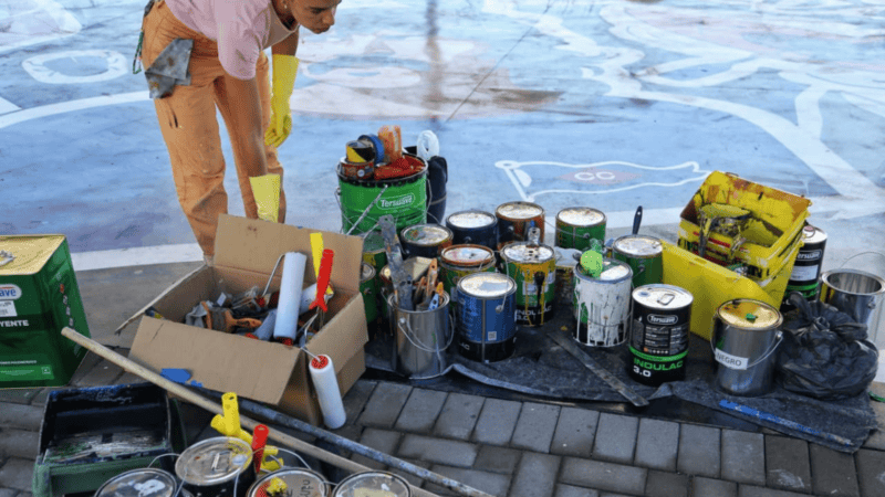 Los artistas trabajan sobre el suelo en el laqueado del mural 