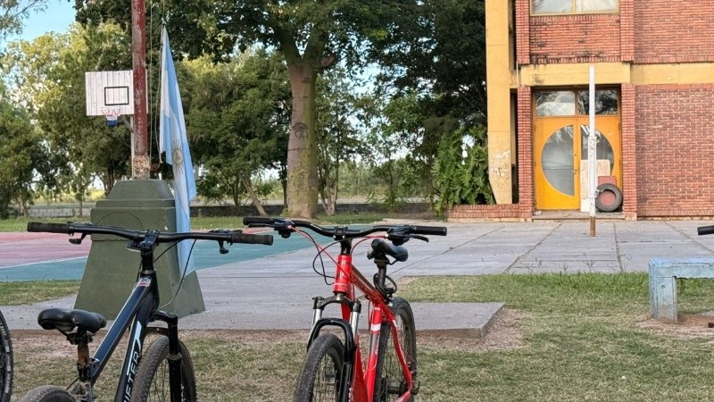 El vidrio roto por un tiro en la escuela, bicicletas que esperan a sus dueños y la bandera a medio subri