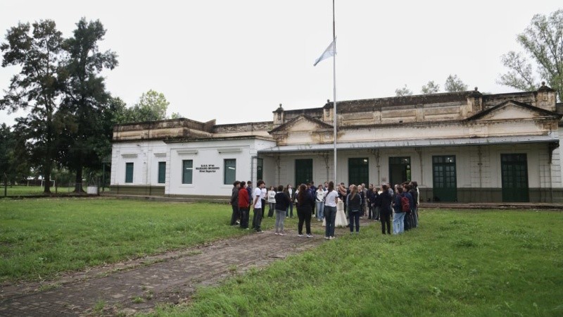 El reducido grupo de alumnos en el izamiento de la bandera, en el jardín de la escuela que da a la calle.