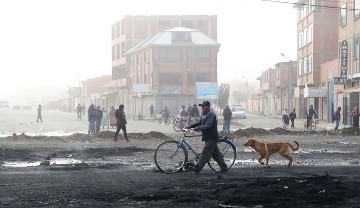 Personas circulan por un vía bloqueada en la carretera de La Paz con Oruro este sábado, en Ventilla (EFE).