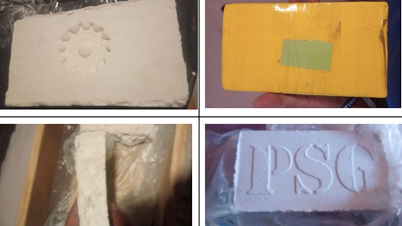 El pesaje de un ladrillo de aparente cocaína estampado con el sello en bajorrelieve de las iniciales 