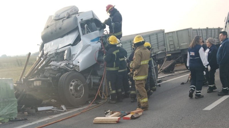 Bomberos trabajando para rescatar al conductor atrapado.