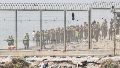 Fuerzas auxiliares de Marruecos impiden la llegada al espigón de la playa del Tarajal que separa Ceuta de Marruecos. (EFE)