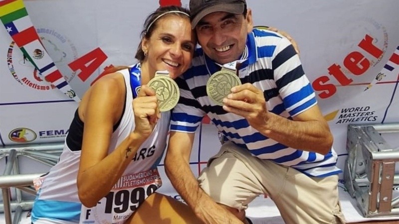 Marisol Tozzi con las medallas y su entrenador José María Villagra, tras el éxito en el XVII Campeonato Sudamericano Máster de Atletismo de Chile