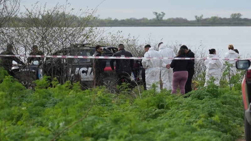 Los peritos forenses en el Corsa incendiado.