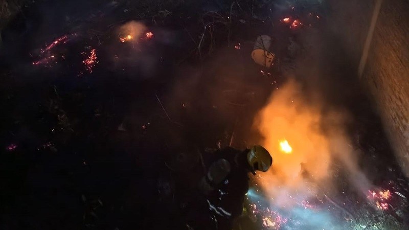 Bomberos Voluntarios trabajando en el baldío incendiado.