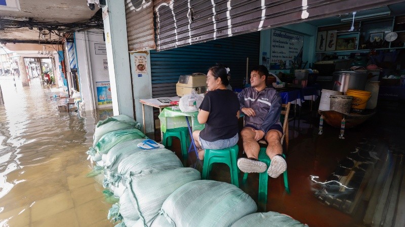 Vendedores observan el agua de la inundación desde su puesto de fideos tras el prolongado aguacero en Bangkok, Tailandia, el 27 de septiembre de 2026. Foto EF.&nbsp;