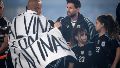 El saludo de Fabio Santana, envuelto con la bandera de Malvinas, y Leo Messi después del himno.