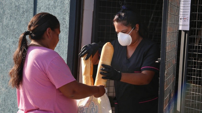Una mujer entrega pan, con un barbijo. (Alan Monzón/Rosario3)