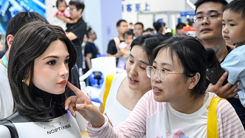 Una visitante observa sorprendida a un robot humanoide en la World Robot Conference 2026&nbsp;