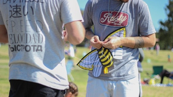 Dos jóvenes solucionan un problema en un barrilete en forma de abeja.